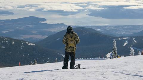 snowboarder standing with lake in background