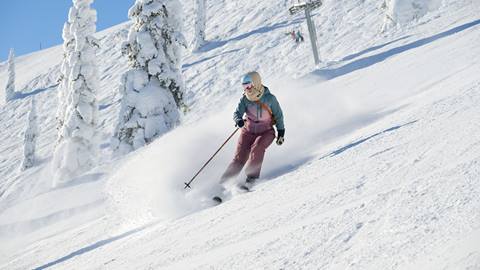 sunny ski woman groomed run Schweitzer snow