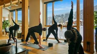 people holding a yoga pose inside with snowy mountain in background