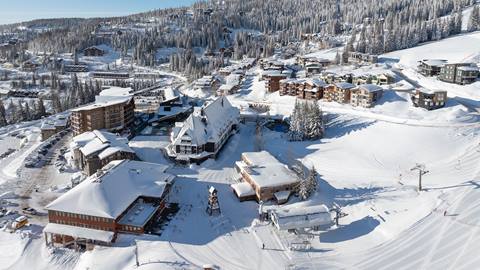 Drone view of snowy village next to ski slopes