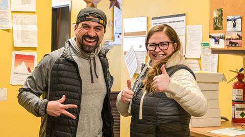 Pair of guest service agents smiling giving hand gestures