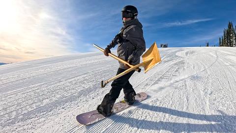 woman snowboarding with golden shovel