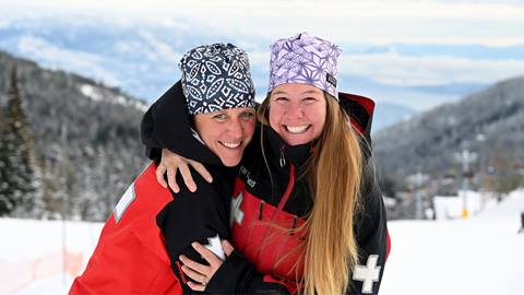 two female ski patrollers smiling embracing