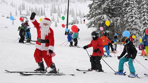 Group of kids following Santa down the slope with balloons