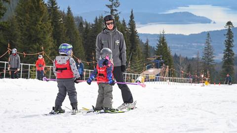 Ski instructor with two small skiers at Schweitzer with a lake view. 