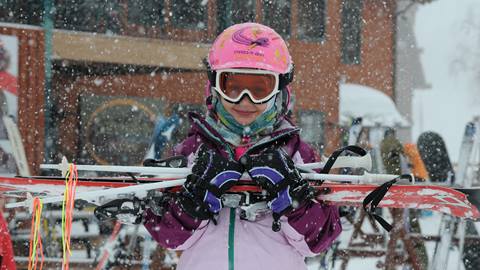 Young skier in a helmet ready for her beginner lesson at Schweitzer. 