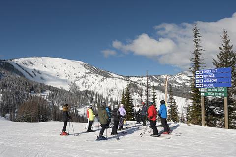 A ski club group on a mountain tour with a view of Schweitzer's Outback Bowl