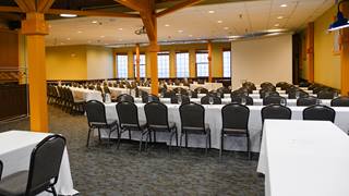 Caribou Room set up for a meeting with long tables and chairs in front of a large screen . 