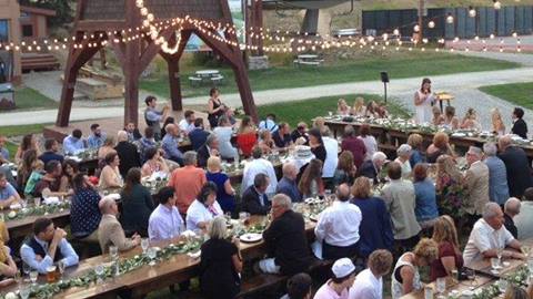 People sitting at long tables with bride speaking for a wedding dinner at Schweitzer in the village