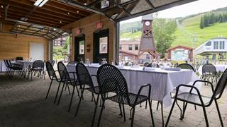 Tables and chairs set up with large garage style door open to the Mountain View Patio and clocktower. 