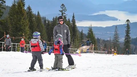 Image of an instructor on the beginner hill with 2 young students and the lakeview in the background