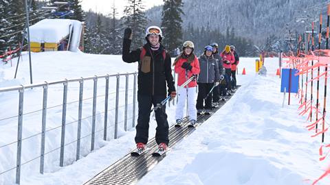 adults riding a magic carpet waving