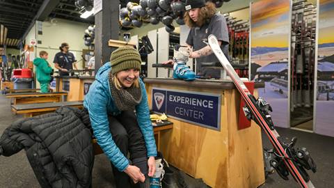 women smiling while putting on ski boots