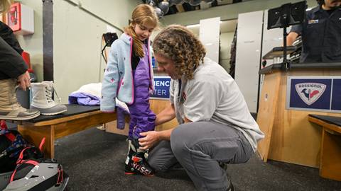 child getting fitted for ski boots with rental tech