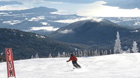 Skier with a stunning view of Lake Pend Oreille in the background at Schweitzer