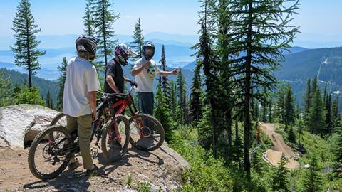 Three advanced mountain bikers scoping out a jump line. Pre-ride, Re-Ride, Free-Ride