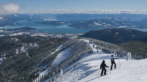 Two skiers on the ridge with the lake in the background