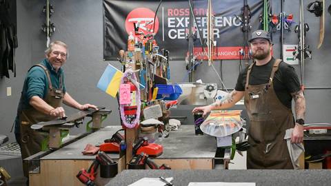 Two repair techs standing over their work benches.