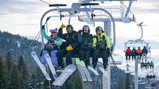 skiers and snowboarder on chairlift smiling