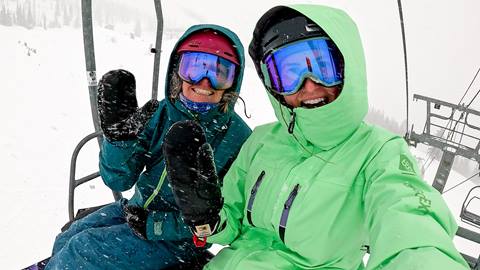 Two people on a chairlift while it's snowing