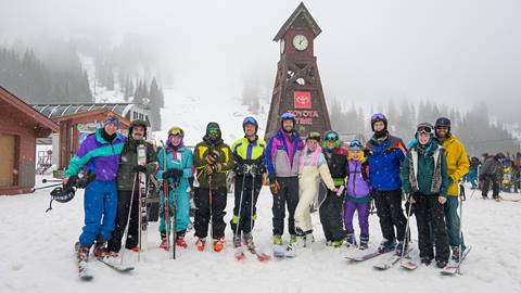 large group of skiers and boarders posing at the clocktower