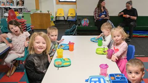 young kids smiling and eating around a table