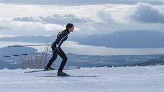 Young athlete Nordic skiing with lake in the background